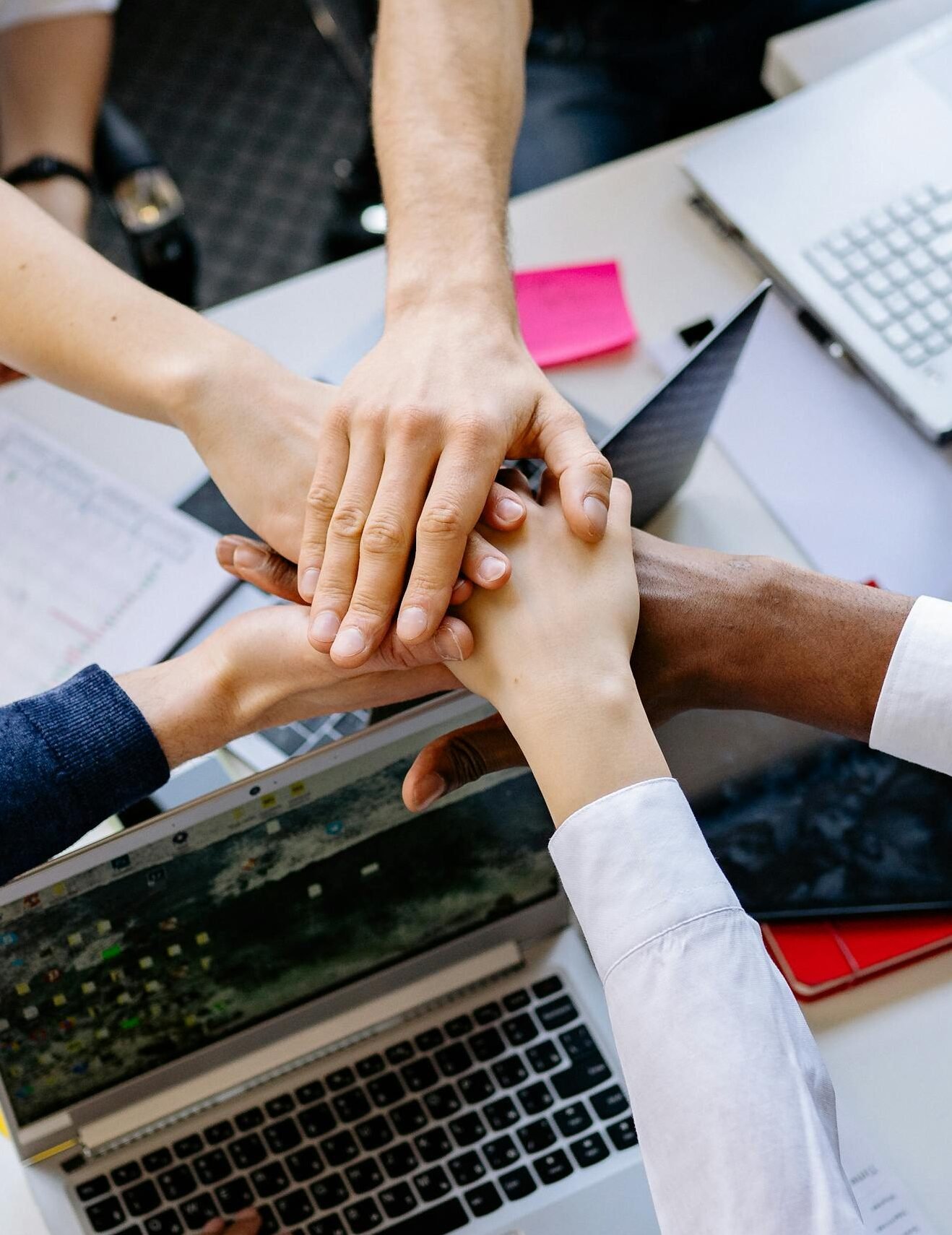 A diverse group of professionals stacking hands over a table symbolizing teamwork and collaboration.