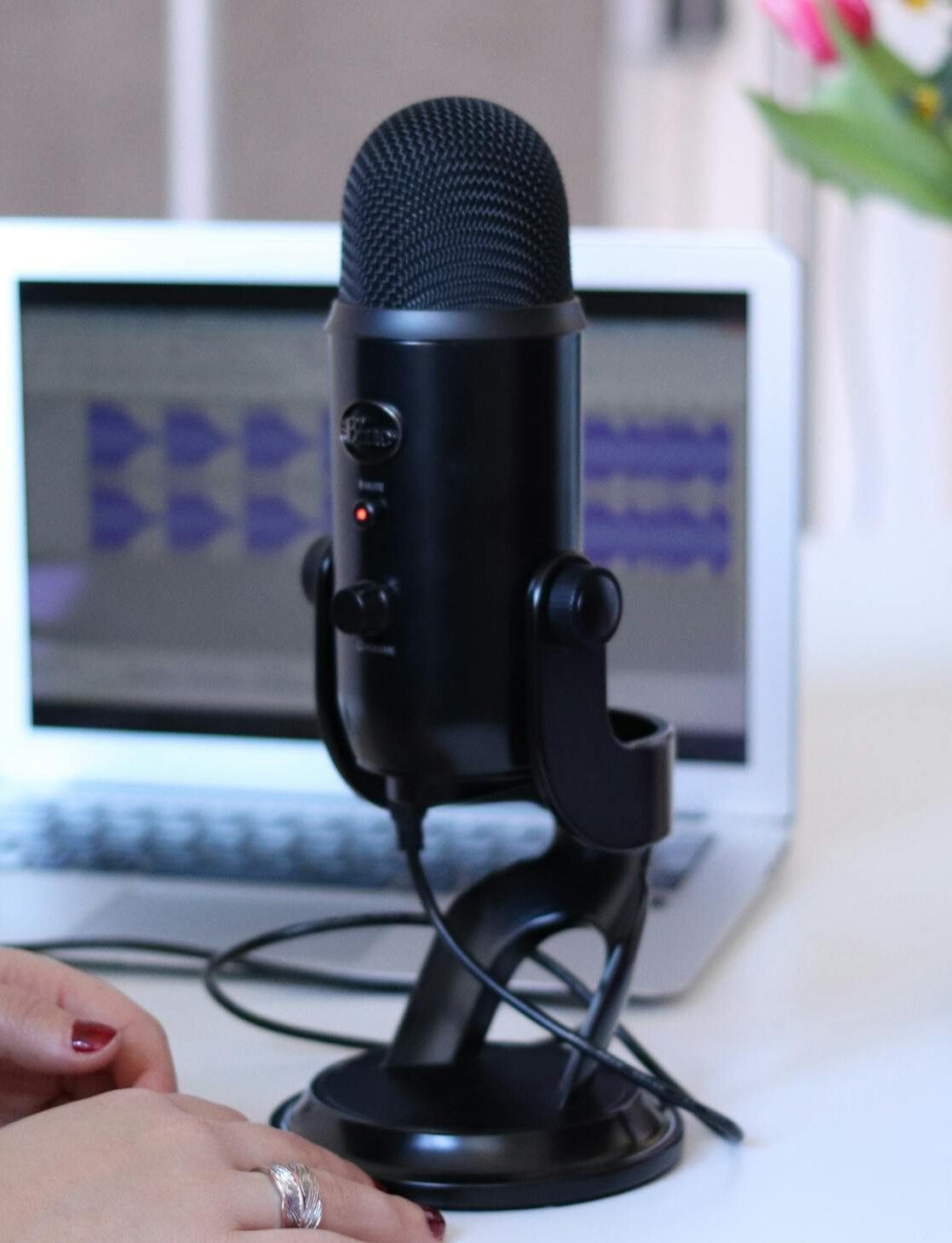 Two women recording a podcast in a modern office with a microphone and laptop.